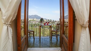 Un balcón con mesa, sillas y vistas a un paisaje montañoso.