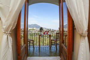 Un balcón con mesa, sillas y vistas a un paisaje montañoso.