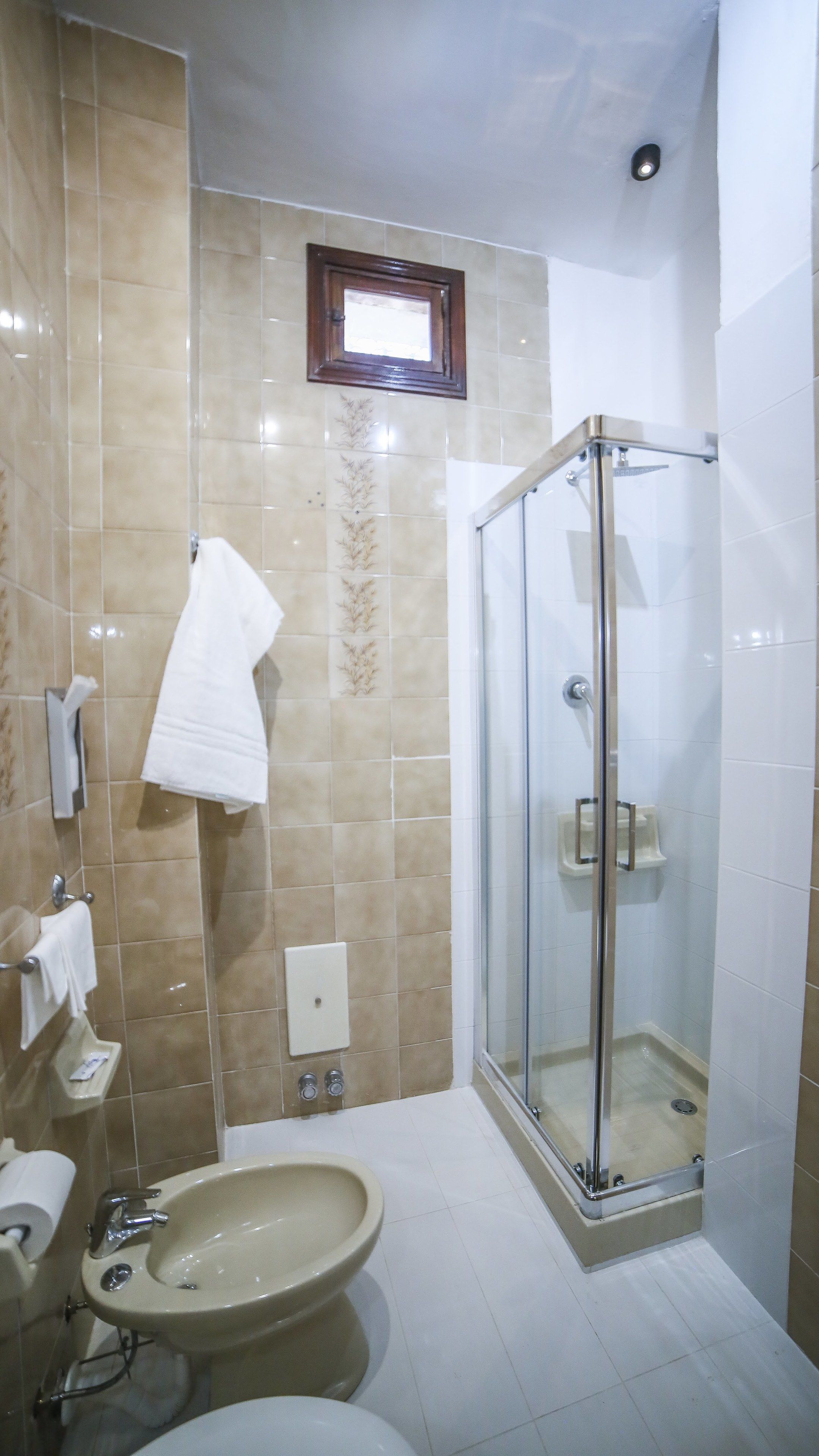 A bathroom with a glass-enclosed shower, a sink, a toilet, and a towel rack.