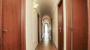 Un largo y estrecho pasillo con puertas de madera a ambos lados, que conduce a varias habitaciones.