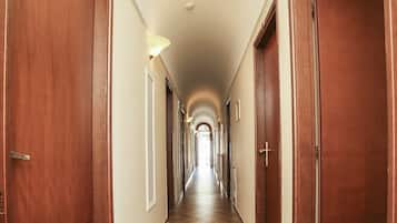 Un lungo e stretto corridoio con porte in legno su entrambi i lati, che conduce a diverse stanze.