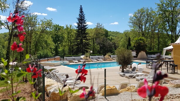 Un espace piscine avec des chaises longues et une piscine entourée d’une clôture.