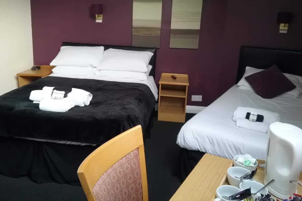 A hotel room with two beds, a desk with a coffee maker, and a chair.