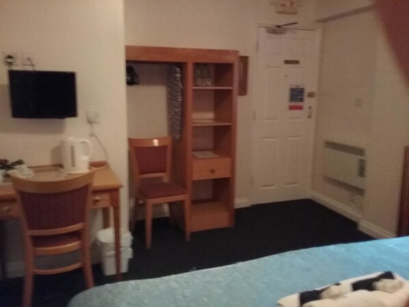A hotel room with a bed, a desk, a chair, a wardrobe, and a television on the wall. - The Prince Consort (Southampton)