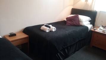 A hotel room with a bed, a bedside table, a nightstand, and a lamp.