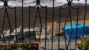 Een balkon met uitzicht op de oceaan, met een rotsachtige zeedijk en een blauw zwembad.