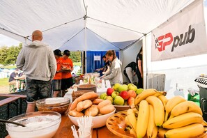 Ein Essensstand mit einer Auswahl an Obst und Brot unter einem Zelt.