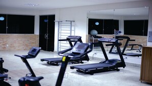 Ein Fitnessstudio mit Laufbändern, Crosstrainern und einer Spiegelwand.