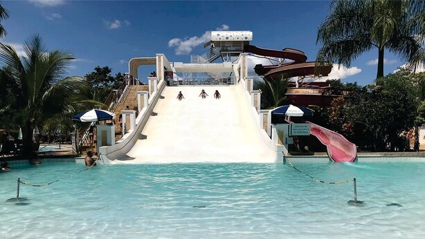 Eine Wasserrutsche in einem Resort, im Vordergrund ein Schwimmbecken.