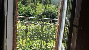 An open doorway leading to a balcony with a wrought iron railing and a view of greenery.