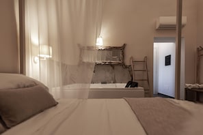 A bedroom with a bed, a bathroom with a bathtub, a ladder, and a door leading to another room. - Terra Mia (Pompei)