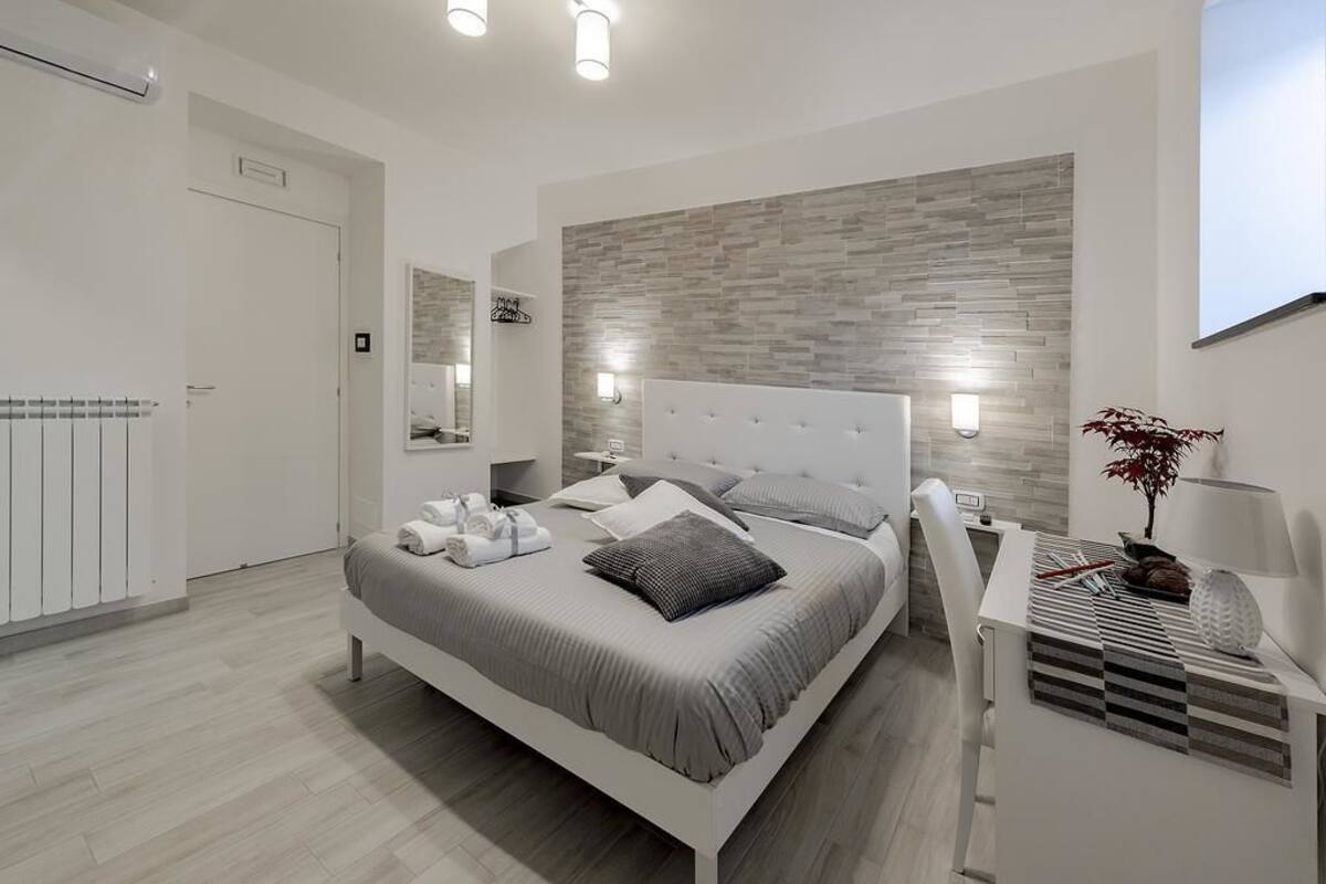Um quarto moderno com uma cama grande, mesas de cabeceira, um espelho e um aplique.