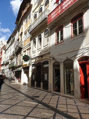 Une rue pavée bordée de bâtiments historiques, dont une pharmacie et une boutique.