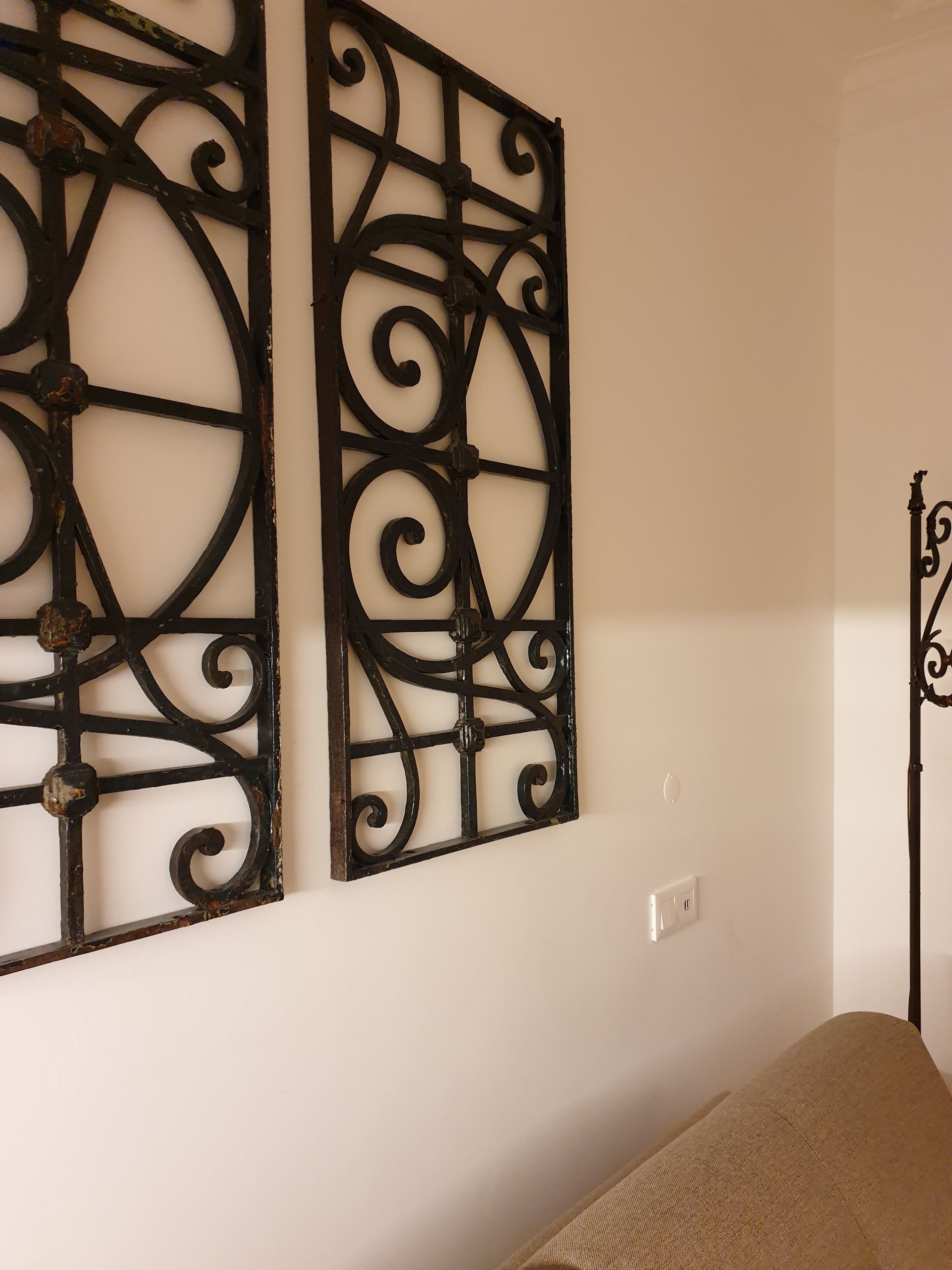 A room with a bed, a wall-mounted decorative metal piece, and a light switch.