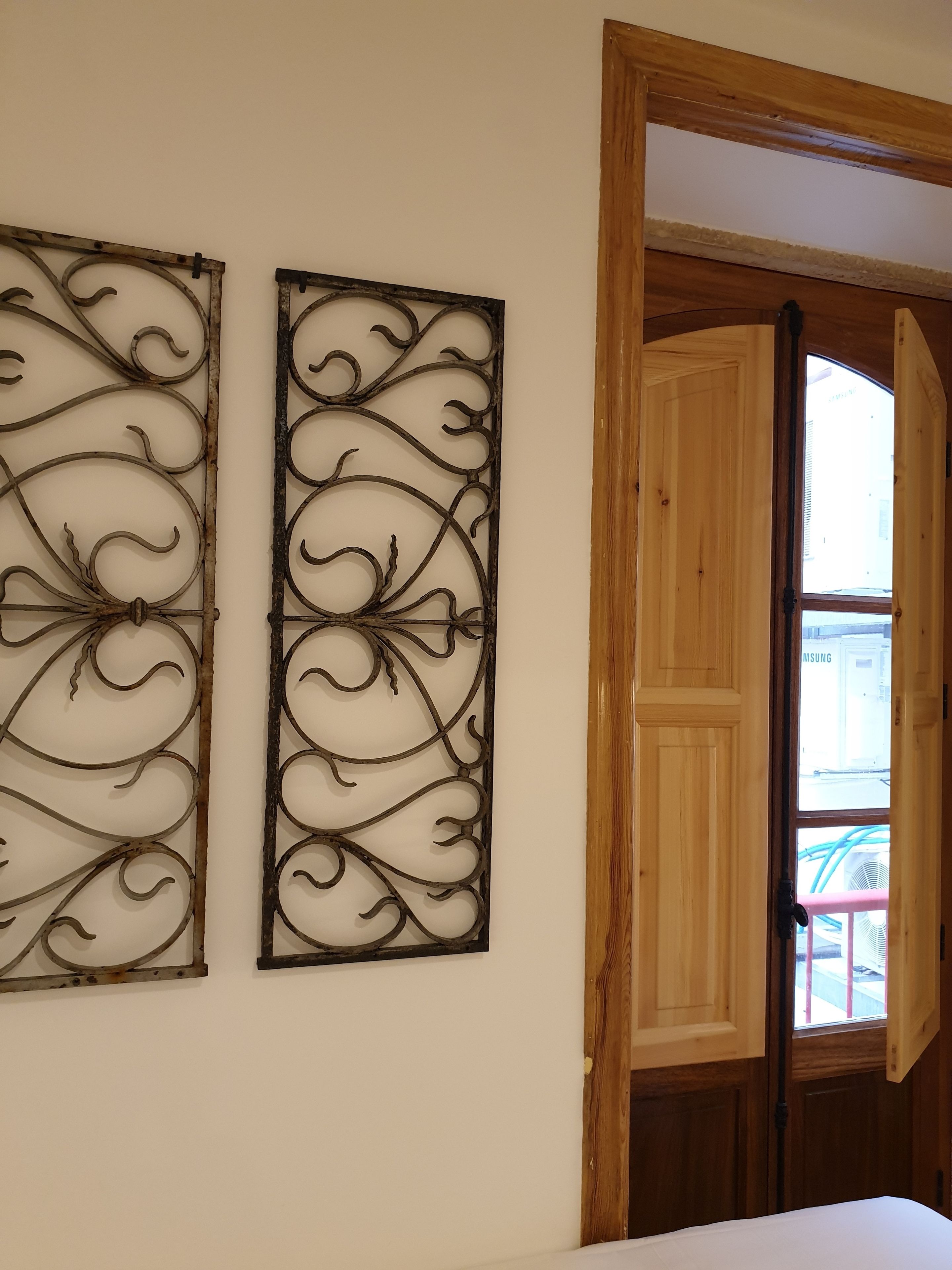 Dos obras de arte metálicas montadas en la pared con diseños elaborados, una puerta de madera y vista al exterior por una ventana.