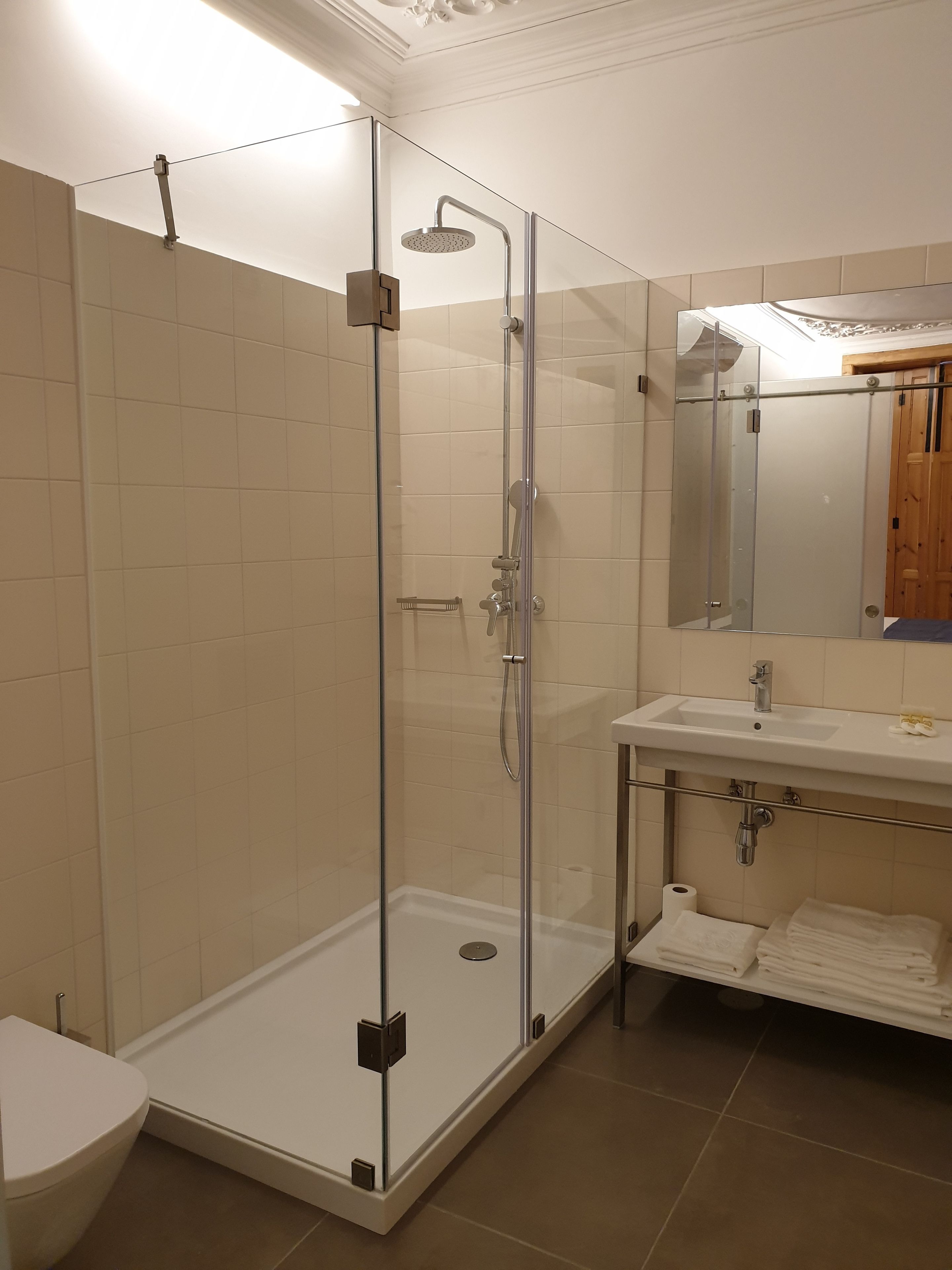 A modern bathroom with a glass-enclosed shower, a white sink, and a wooden cabinet.