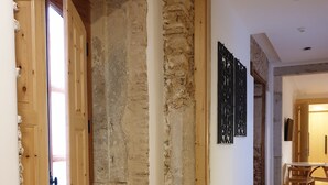 A hallway with a wooden door, stone wall, and a staircase leading to another room.