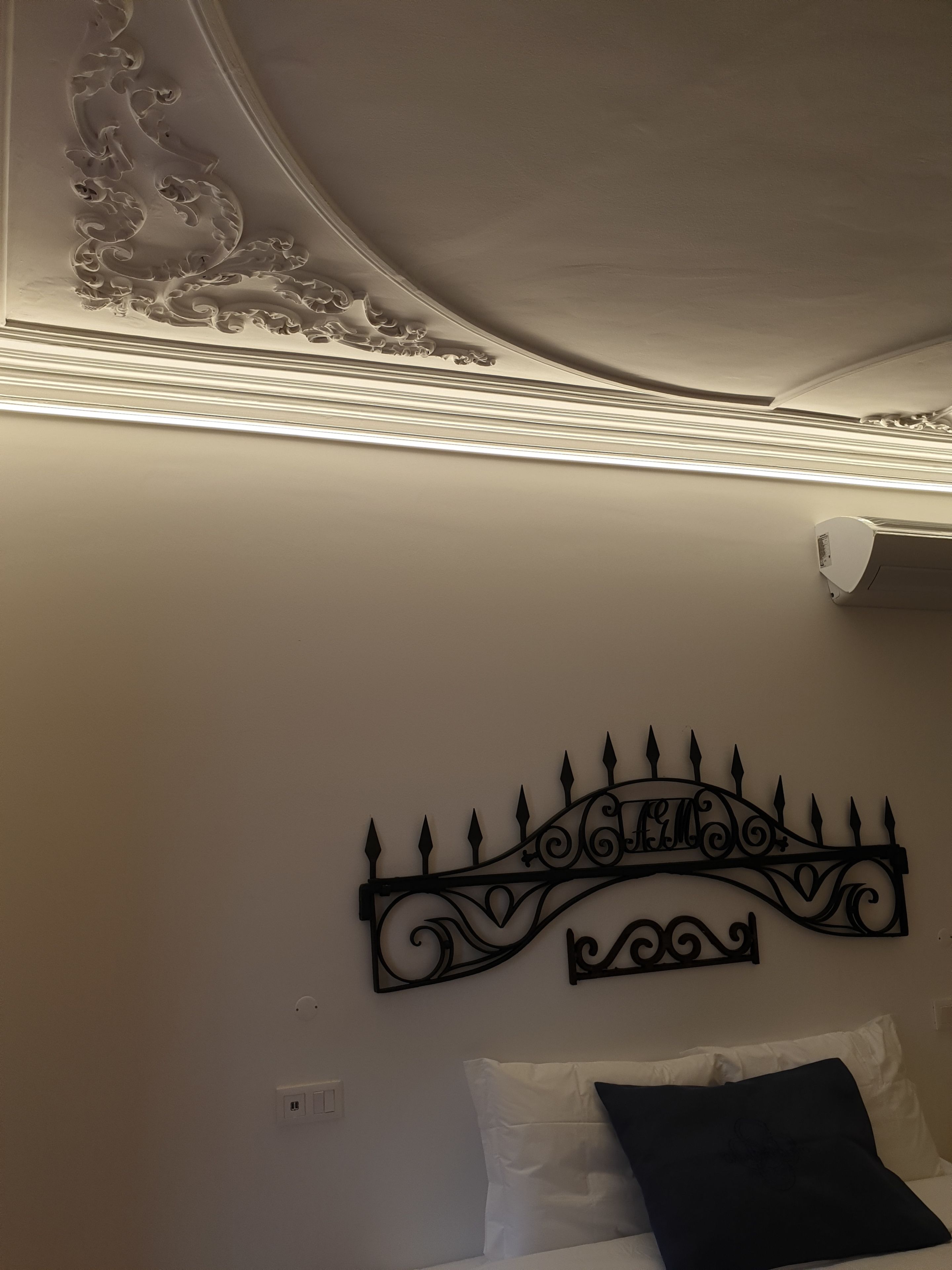 A bedroom with a bed, a decorative metal headboard, and a ceiling with intricate designs.