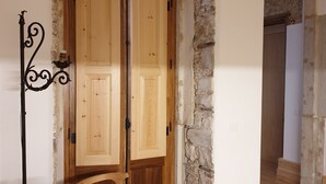 A room with a wooden door, stone wall, and a beige sofa.