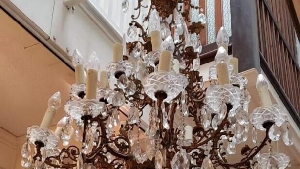 A grand chandelier with multiple crystal tiers hanging from a white balustrade. - Anys Bed and Breakfast (Mexico City)