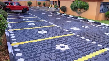 Um espaço de estacionamento com piso padronizado, um veículo vermelho e um edifício com telhado vermelho.