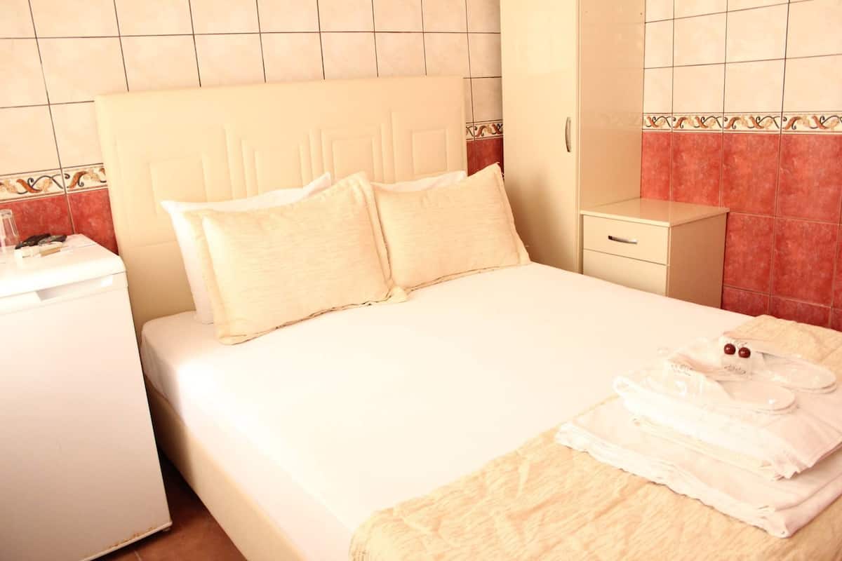 Een hotelkamer met een bed, nachtkastje, lade en een badkamergedeelte.
