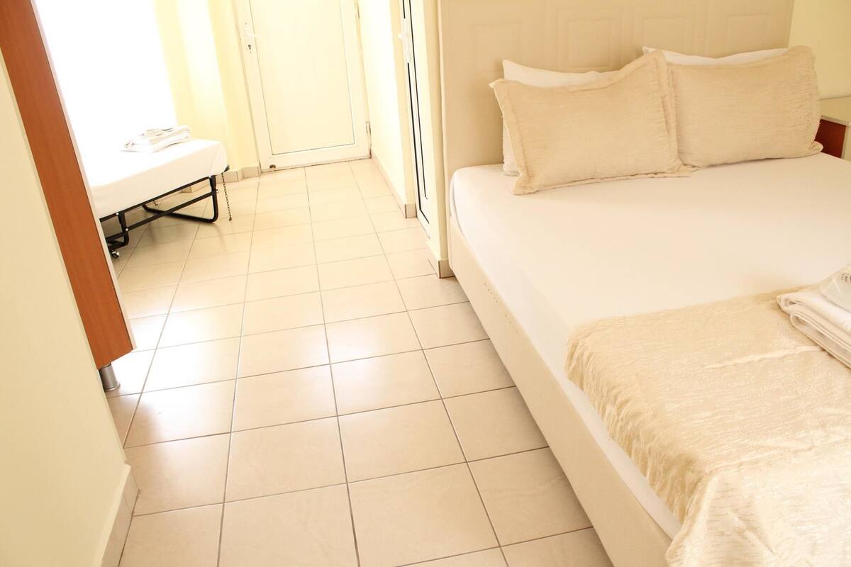 Een hotelkamer met een bed, een bankje en een deur naar een balkon.