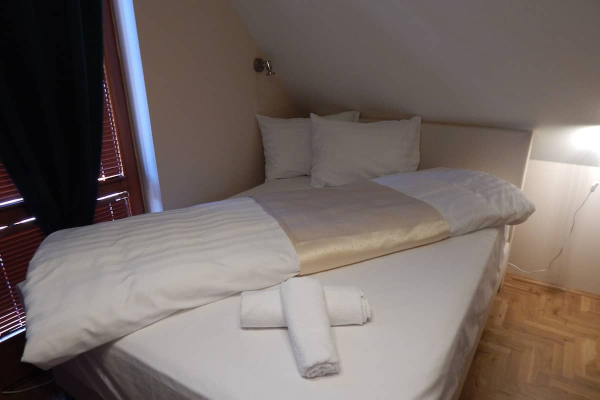 A neatly made bed with white linens and a folded towel.