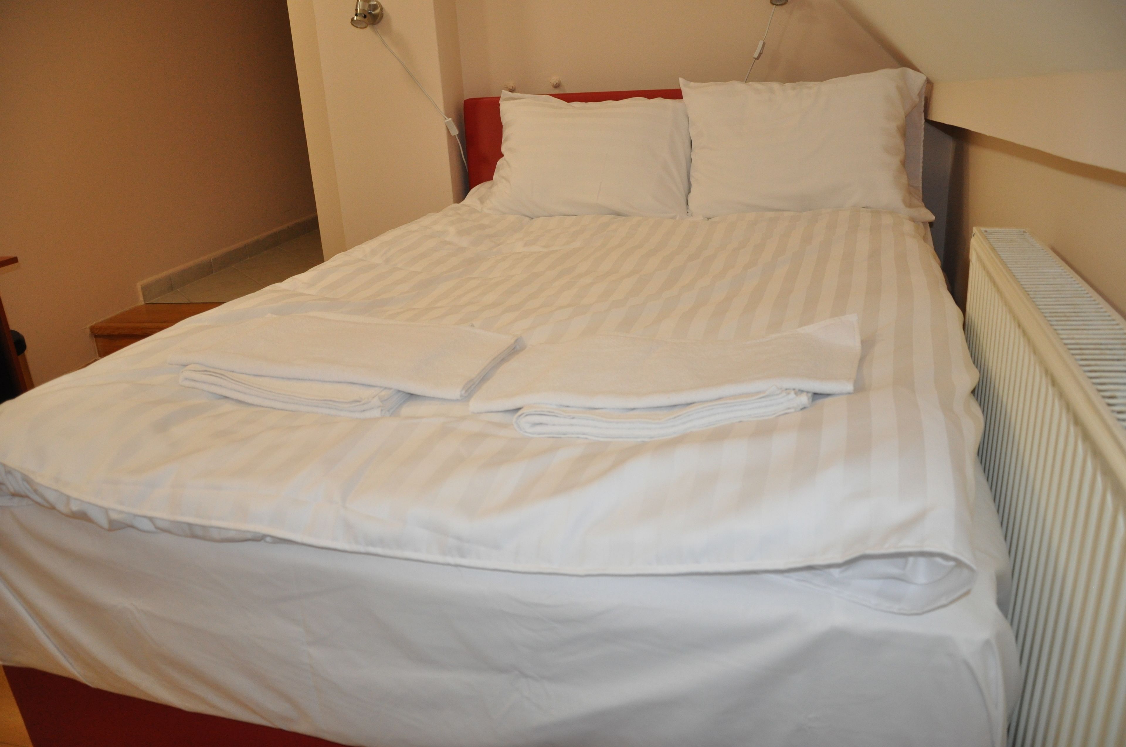 A neatly made bed with white linens and two folded towels.