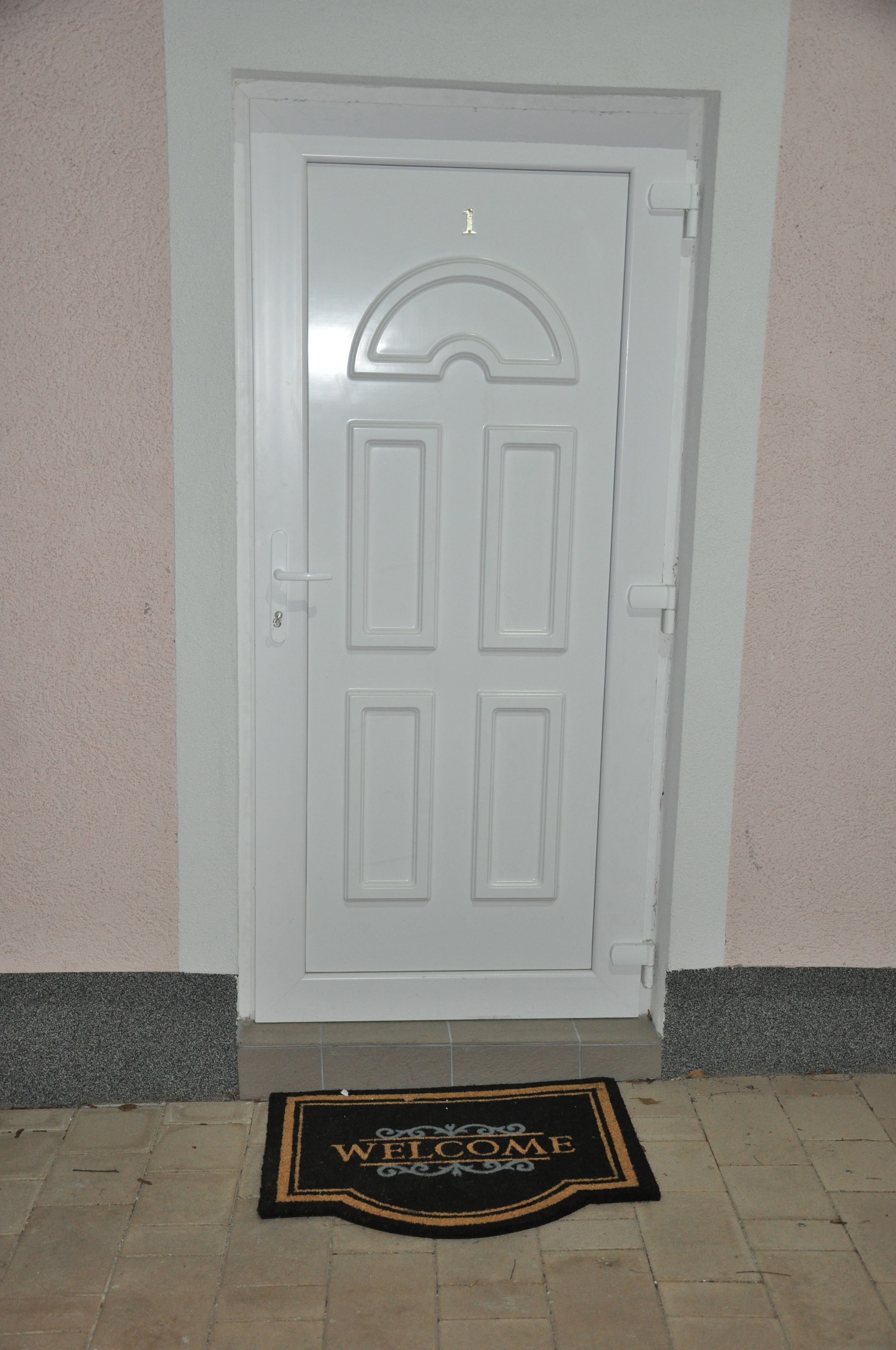 A white door with a welcome mat in front.