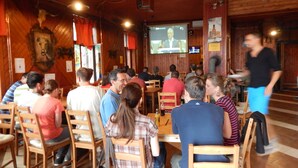 Ein Restaurant mit Holzwänden und einem großen Bildschirm, der eine Nachrichtensendung zeigt.