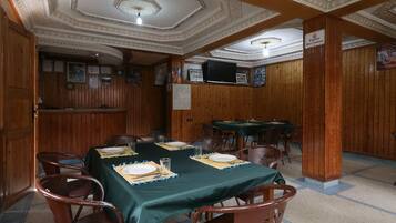 Un comedor con una larga mesa dispuesta para seis comensales, paneles de madera en las paredes y un techo con diseños elaborados.