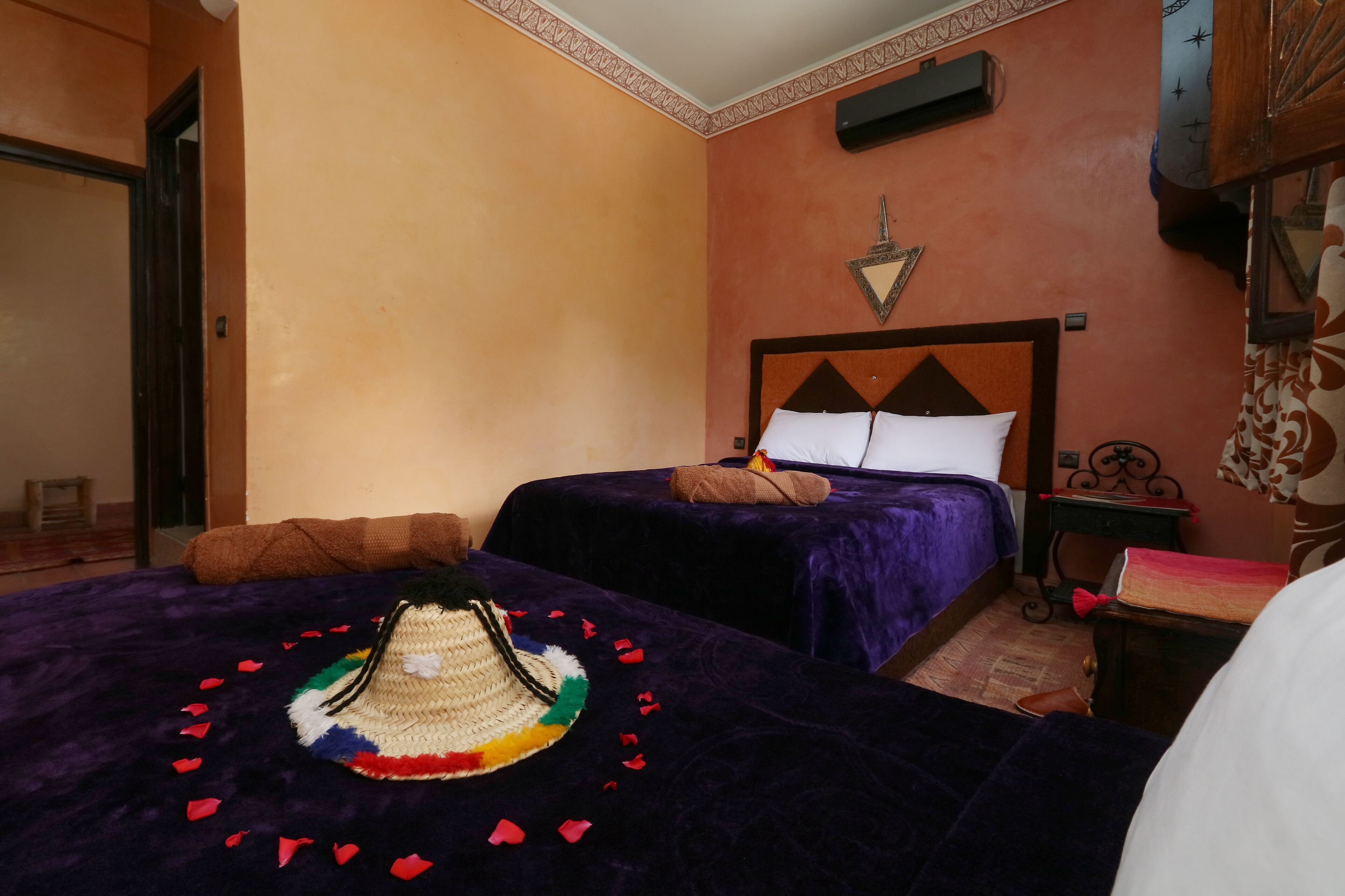 Une chambre d’hôtel avec deux lits, une décoration murale et une petite table sur laquelle se trouvent un livre et une lampe.
