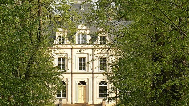 A symmetrical building with a central entrance, flanked by trees and a gravel pathway leading to it. - Schloss Lanke (Wandlitz)