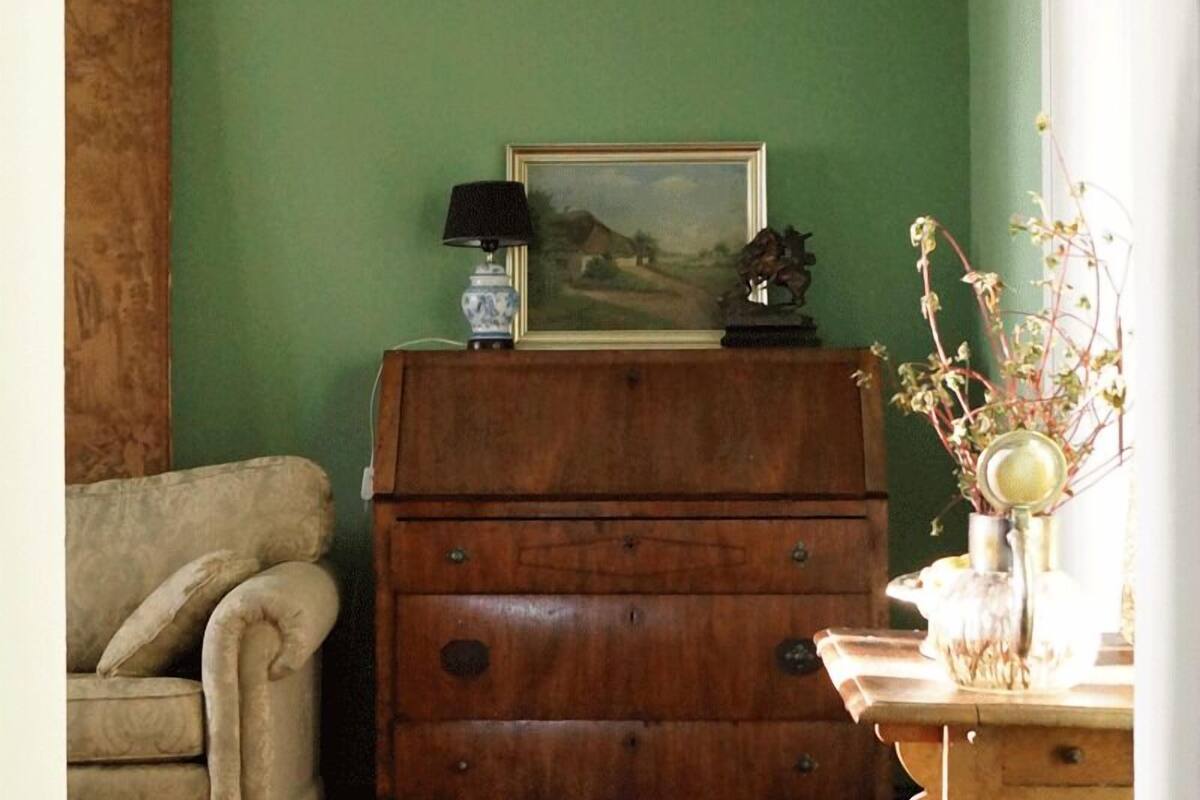 Una habitación con un aparador de madera, una silla y una mesa con un florero.