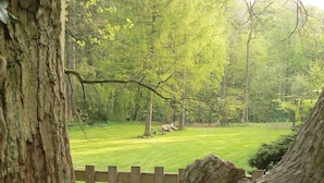 A park with a wooden fence, trees, and a grassy area. - Schloss Lanke (Wandlitz)