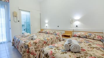 Habitación de hotel con dos camas, un baño y una puerta de vidrio que da a un balcón.
