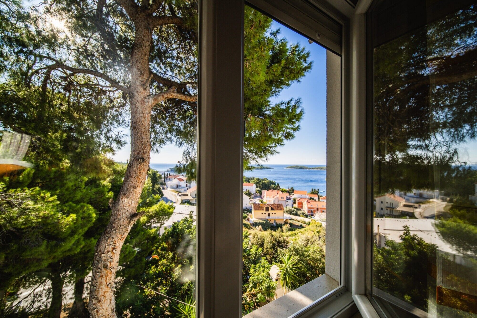 A window view of a coastal town with houses and a clear sky.