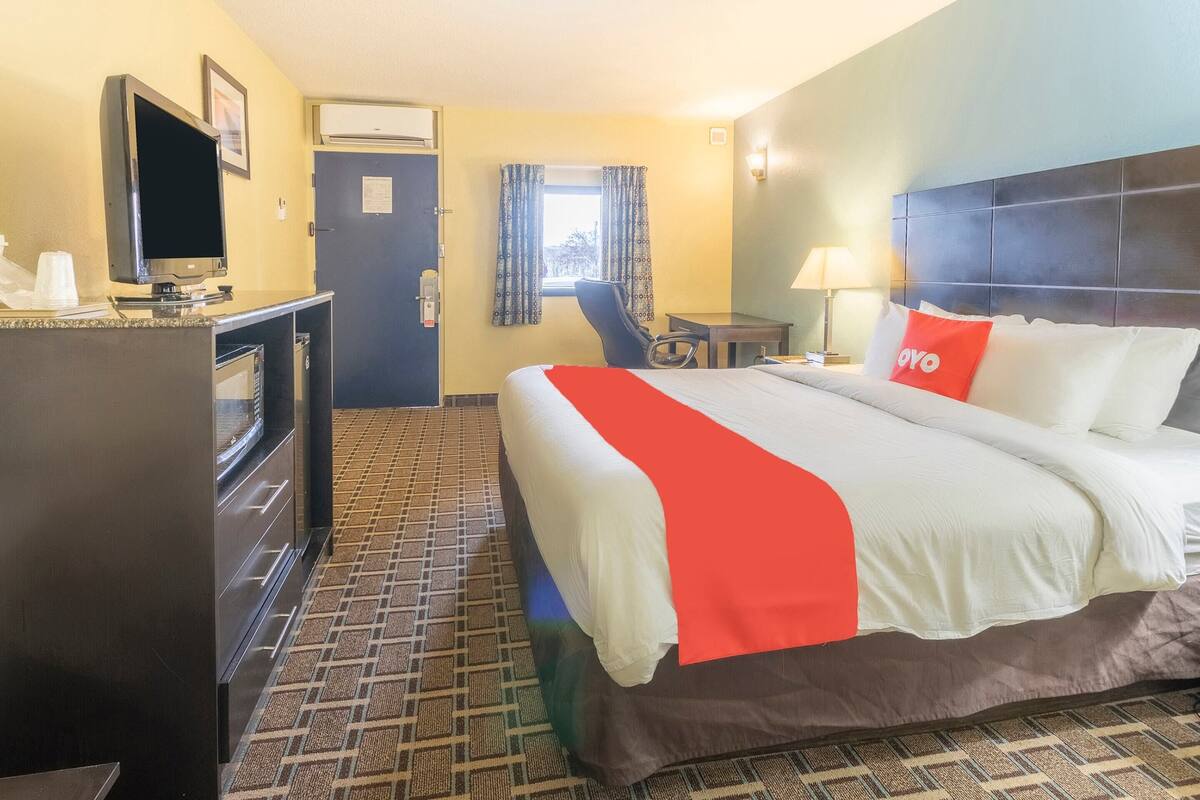 Una habitación de hotel con cama, escritorio, silla, televisor y minibar.