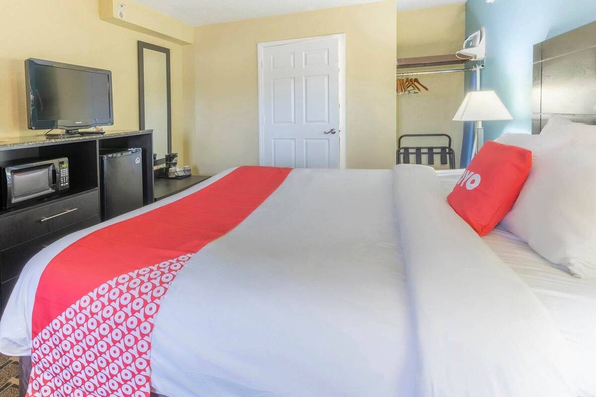 Una habitación de hotel con cama, televisor, microondas y puerta.