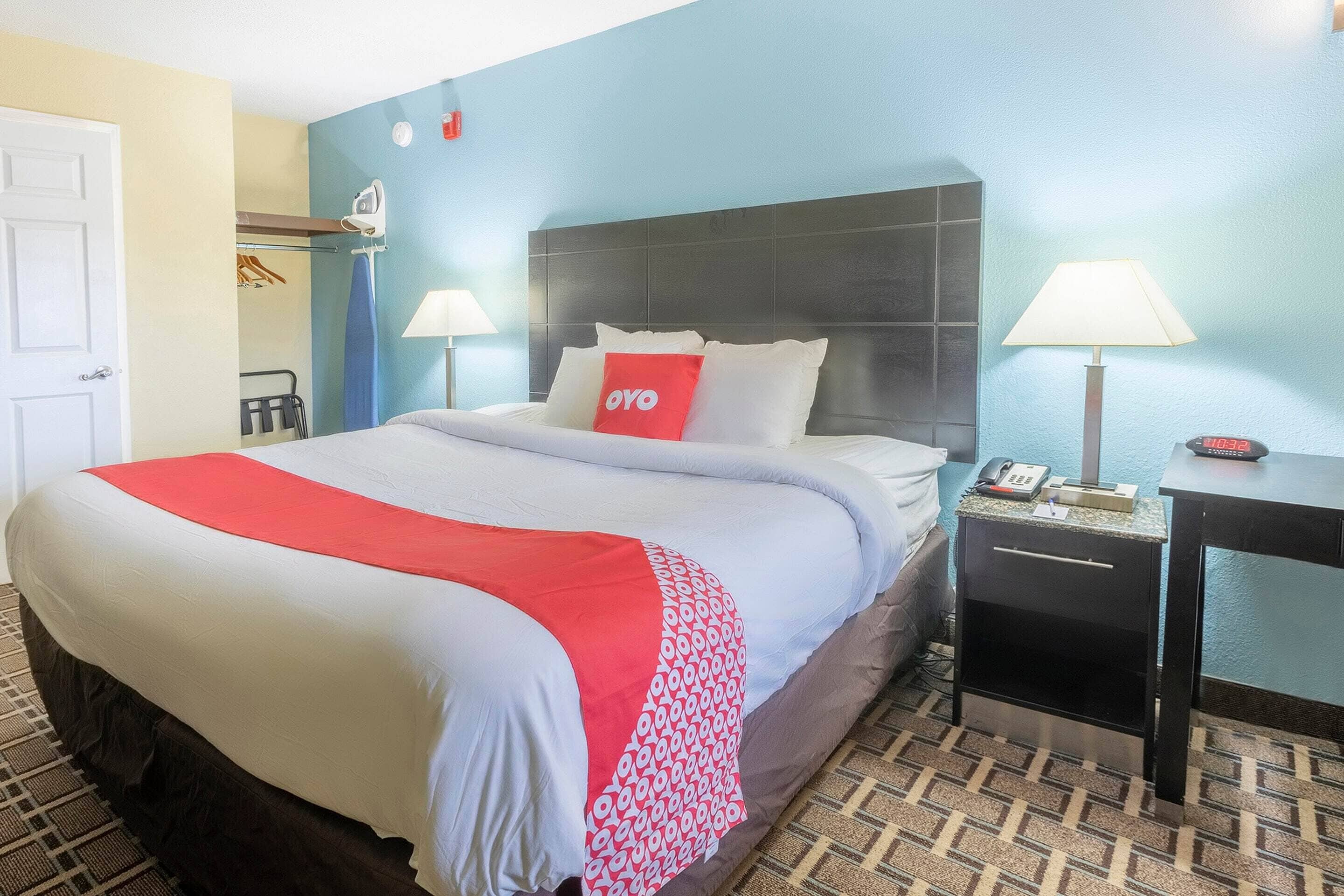 Een hotelkamer met een groot bed, twee nachtkastjes, een kast en een spiegel.