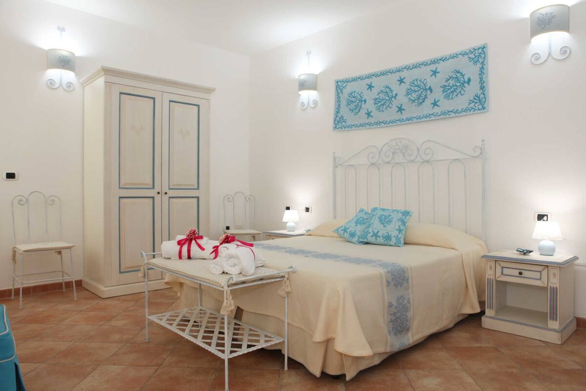 Une chambre à coucher comprenant un lit, des tables de chevet, une armoire et une petite table avec des serviettes.
