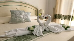 Un lit avec deux serviettes disposées en forme de cygnes, des oreillers, une lampe et une fenêtre avec des rideaux.