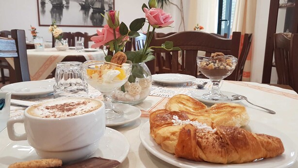 Une table à manger dressée avec une tasse de café, un croissant, un bol de dessert et une assiette de pâtisseries.