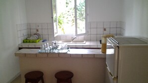 Eine Küche mit Fenster, Spüle und zwei Barhocker.