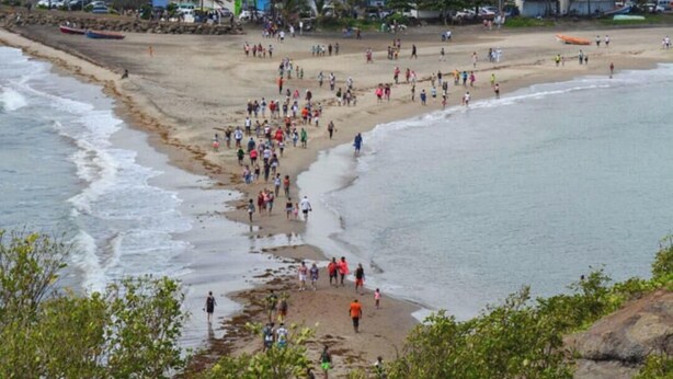 Ein Strand mit Menschen, einer Kirche und Gebäuden im Hintergrund.
