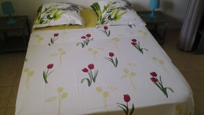 Ein Bett mit floraler Bettwäsche, zwei Nachttische und ein Beistelltisch.