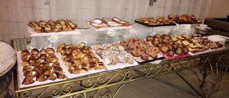 A buffet table with various baked goods and pastries.