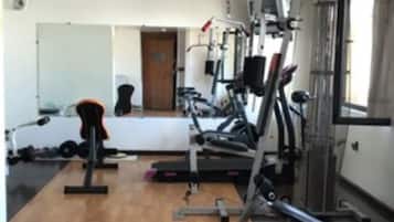 A gym with various exercise equipment, a whiteboard, and a door in the background.