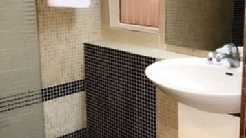 A bathroom with a shower, a sink, and a mirror.